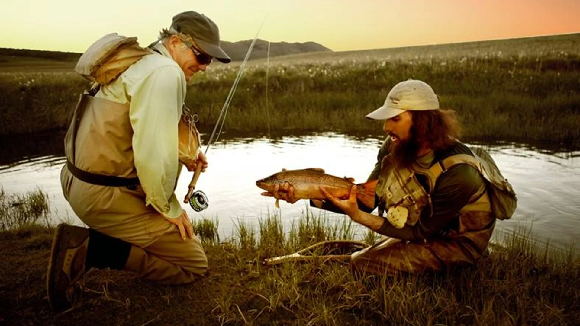 Win Harris and Guide with Large Brown Angler kneeling with fly rod and guide with large browwn